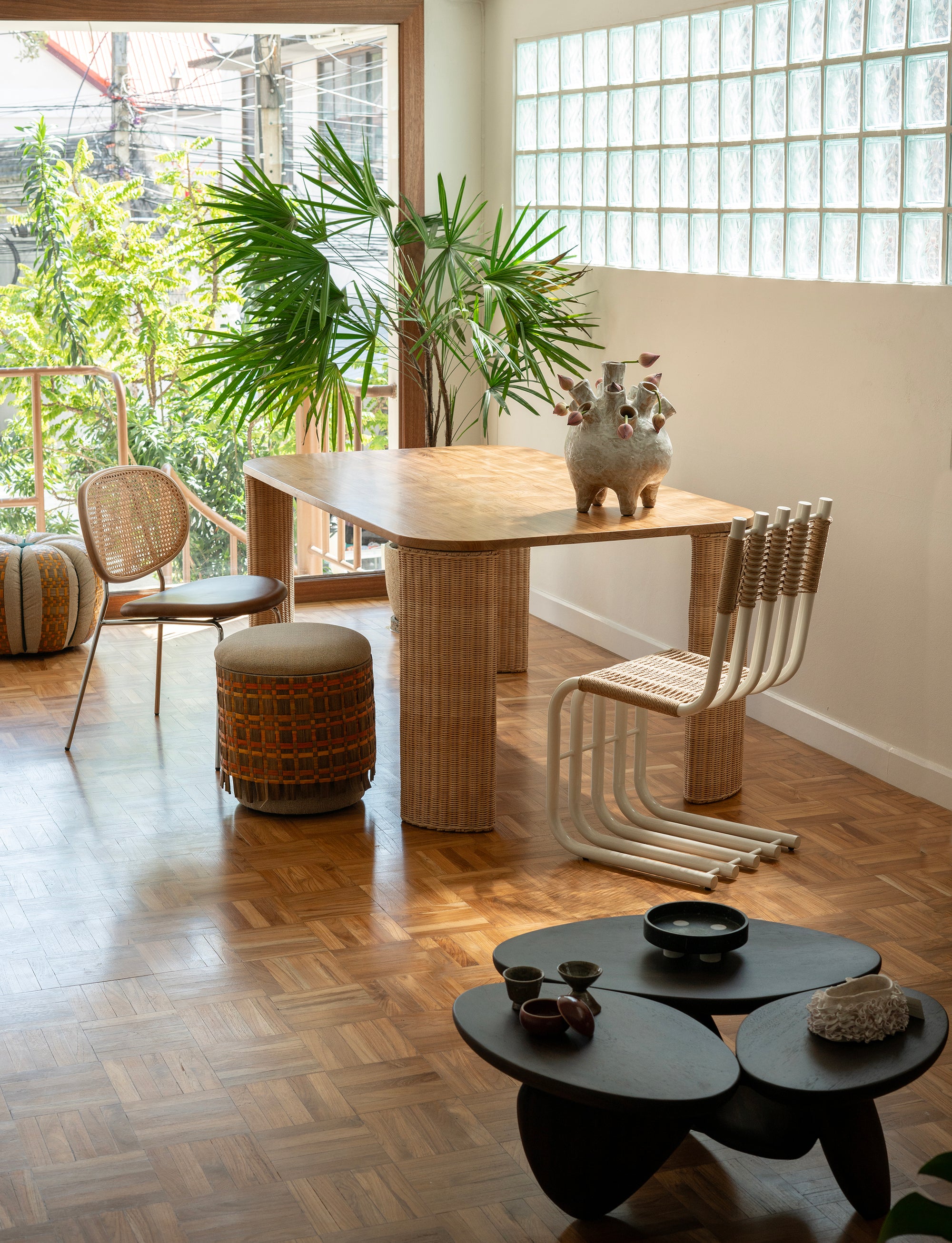 OTS Chair in cream powder-coated steel with white handwoven cotton seat, designed by Office of Tangible Space, shown on wooden floor among tables, chairs, and other objects.